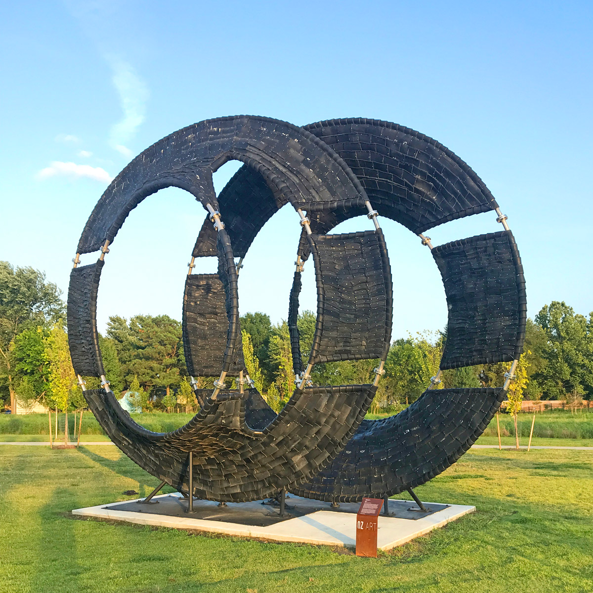Déjà Vu by Chakaia Booker, a large ring sculpture of black tires and steel in Osage Park, Bentonville