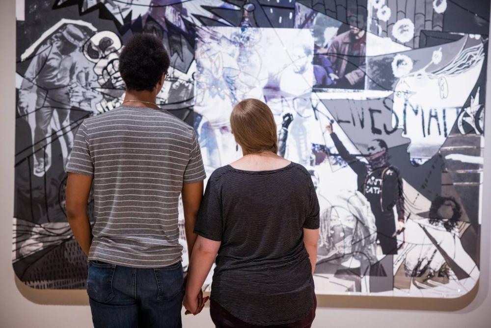 Two visitors looking at Mickalene Thomas's large black and white Guernica work at Crystal Bridges