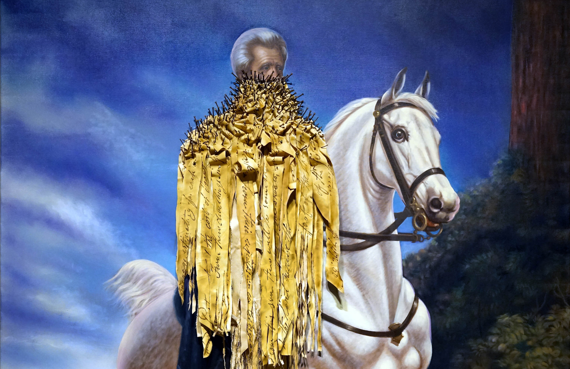 The Cost of Removal by Titus Kaphar, a painted rider on a white horse covered in nailed gold fabric strips